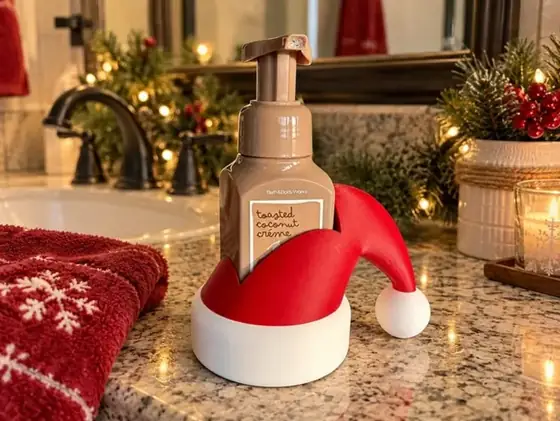 Porta jabón rojo y blanco con forma de gorro navideño que sostiene un dispensador