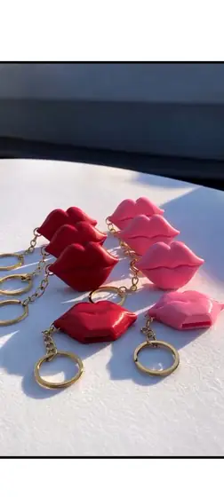 Llaveros en forma de labios rojos y rosados con argollas doradas sobre una mesa blanca