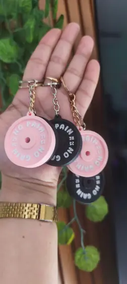 Llaveros con forma de discos de pesa en colores rosado y negro y letras blancas